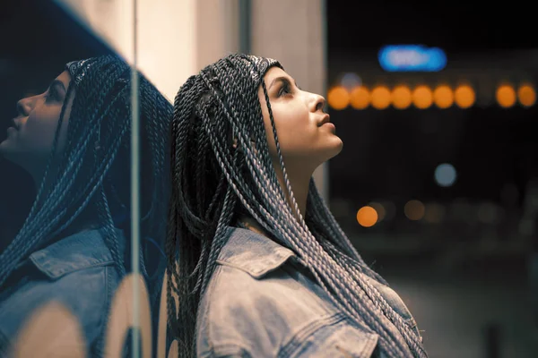 Портрет молодой необычной женщины, опирающейся на здание в ночном городе — стоковое фото