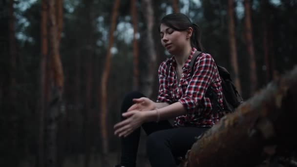 Moe maar gelukkige vrouw zittend op boomstam in het bos en ontspannen — Stockvideo