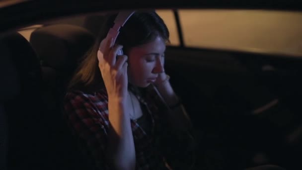 Woman passenger listening to music in a car in stereo headphones — Stock Video