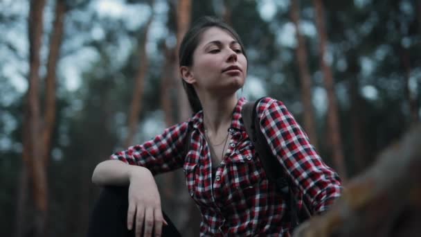 Уставшая, но счастливая женщина сидит на стволе дерева в лесу и расслабляется — стоковое видео