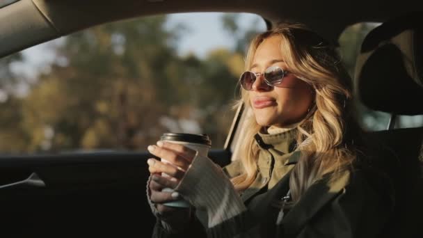 Egy nő forró teát iszik egy autóban. — Stock videók