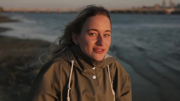 Щаслива жінка розмовляє зі мною, стоячи біля річки в осінній день — стокове відео