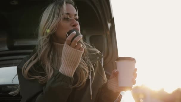 Mulher gosta de outono beber chá quente e comer biscoito perto do carro — Vídeo de Stock