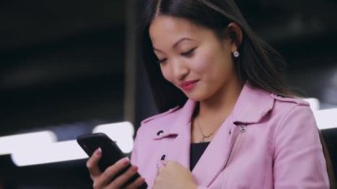 Asyalı kadın cep telefonundan mesaj gönderiyor.