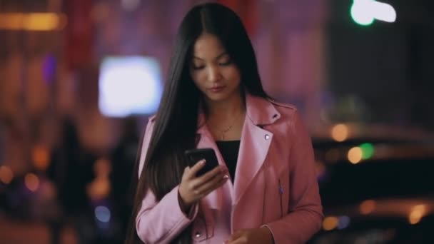 Mulher asiática enviar mensagem de texto no celular à noite cidade — Vídeo de Stock