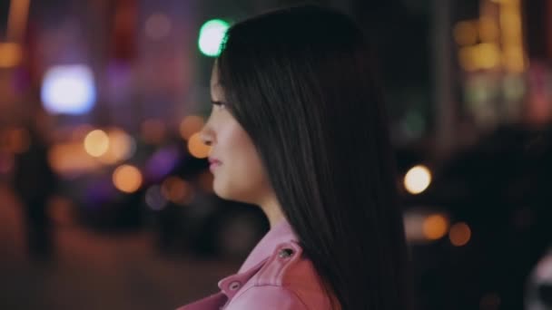 Portret pięknej azjatyckiej kobiety w nocnym mieście obraca twarz patrząc w kamerę — Wideo stockowe