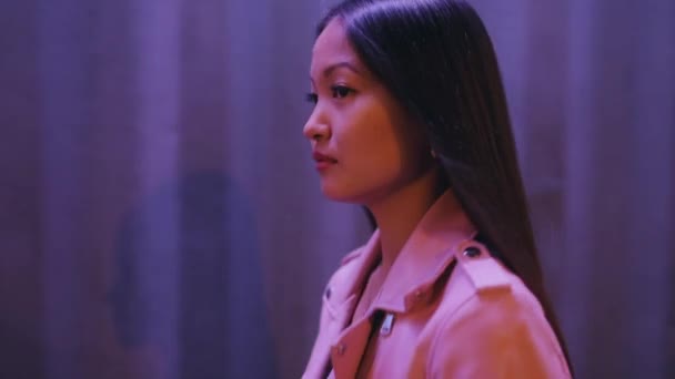 Asiática mujer pone en auriculares caminando en la noche de la ciudad — Vídeo de stock