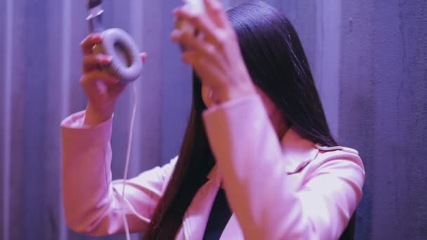 アジアの女性は夜の街を歩くヘッドフォンを置く — ストック動画