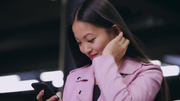 Azjatka wysłać wiadomość SMS na komórkę w nocy miasta — Wideo stockowe