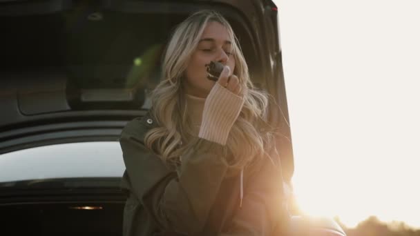 Mulher gosta de outono beber chá quente e comer biscoito perto do carro — Vídeo de Stock