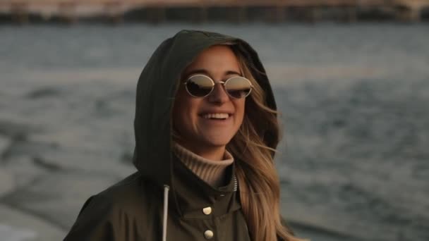 Elegante mujer feliz en gafas de sol riendo de pie en el río — Vídeos de Stock