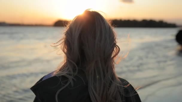 Mulher feliz gosta de pôr do sol e virar a cara olhando para mim de pé perto do rio — Vídeo de Stock