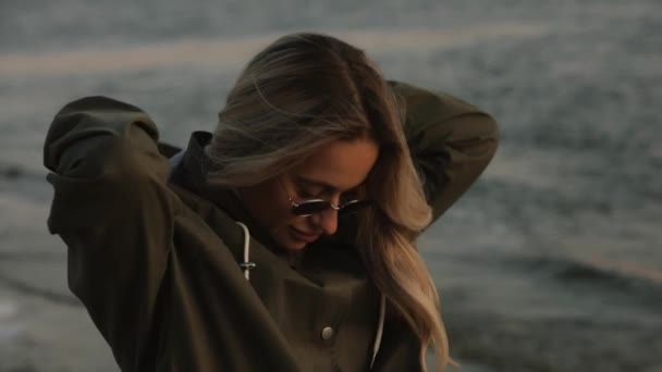 Stylish woman in sunglasses wear hoodie standing at the river — Stock Video