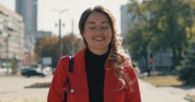 Güneşli sonbahar gününde sokakta yürüyen genç gülümseyen kadın