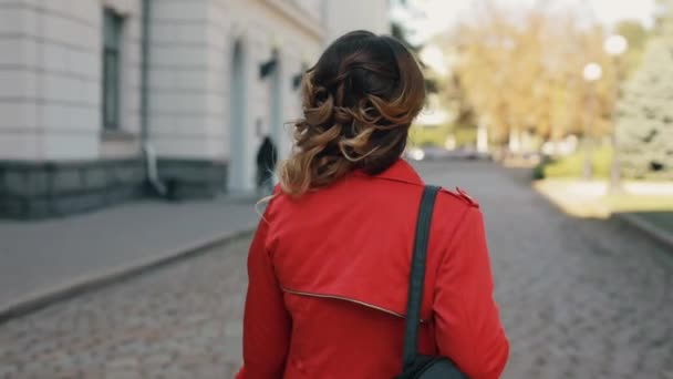 Kvinna går längs gränd på höstdagen ser tillbaka — Stockvideo