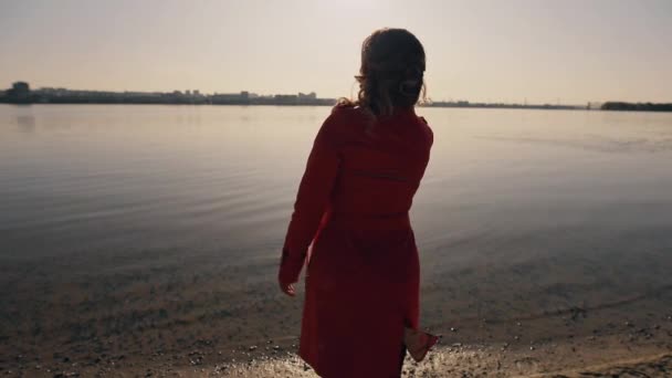 Ensam kvinna som kastar stenen in i flod störd fred, tillbaka beskådar — Stockvideo