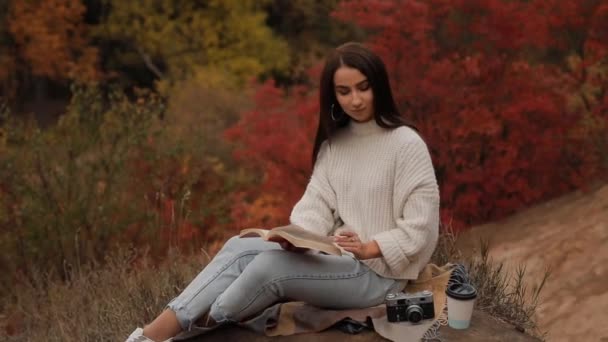 Frau liest Buch sitzend im Herbstwald — Stockvideo