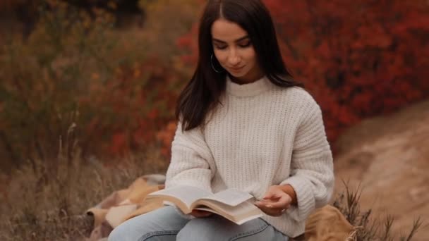 Mujer leyendo libro sentado en el bosque de otoño — Vídeo de stock