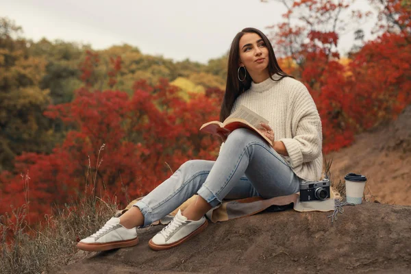 Frau liest Buch sitzend im Herbstwald — Stockfoto