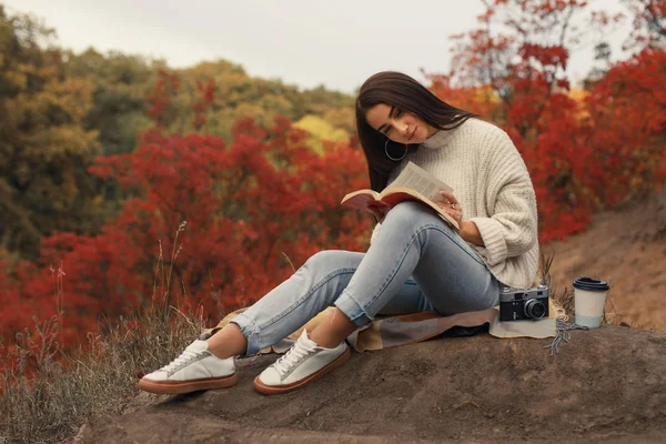 Frau liest Buch sitzend im Herbstwald — Stockfoto