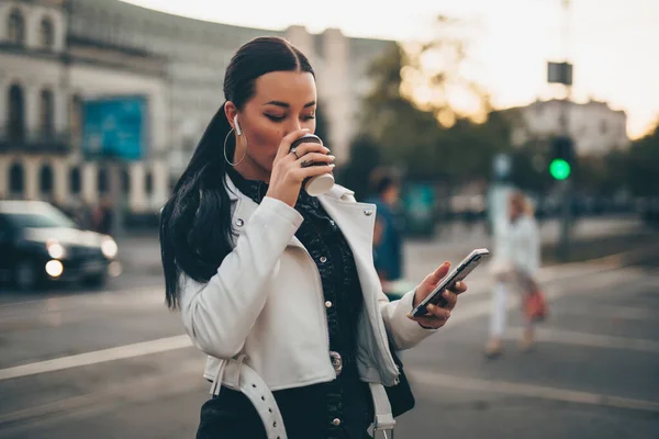 Retrato de mulher usando telefone celular enquanto bebe café em uma rua da cidade — Fotografia de Stock