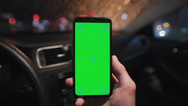 POV, mão masculina segurando smartphone com tela verde em um carro à noite — Vídeo de Stock