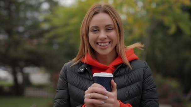 Retrato personal de una hermosa mujer sonriente mirando a la cámara sosteniendo una taza de café — Vídeos de Stock