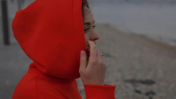 Schöne Frau entspannt sich am Meer in Kapuze — Stockvideo