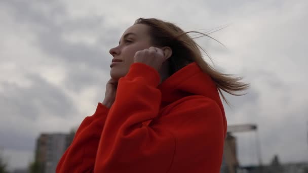 Mujer escuchando música en frío día de otoño, estado de ánimo, nublado — Vídeo de stock