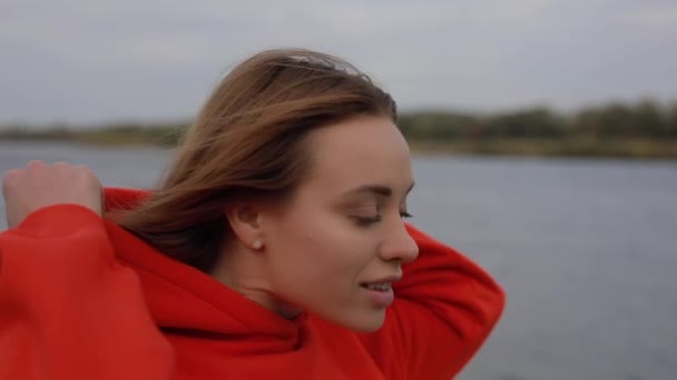 Schöne europäische Frau trägt Kapuze am Fluss — Stockvideo
