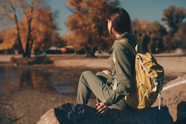 Turistka sedící v blízkosti řeky na podzim — Stock fotografie