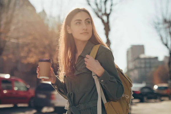 Beautiful woman holding paper coffee cup and enjoying walk in the city — Stok fotoğraf