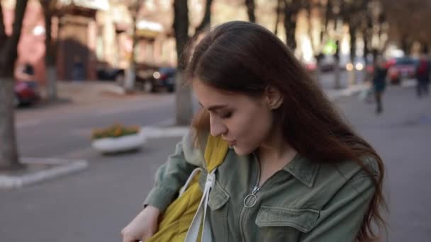 Улыбающаяся милая студентка хихикает, глядя на камеру в городе — стоковое видео