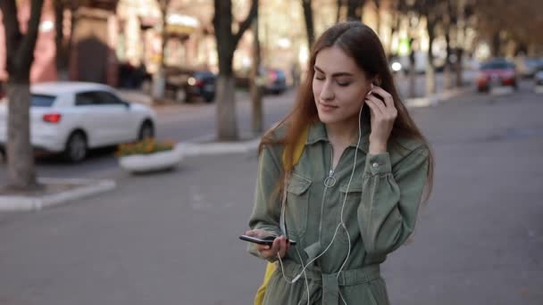 Mulher europeia coloca fones de ouvido e ouvir música na cidade urbana — Vídeo de Stock