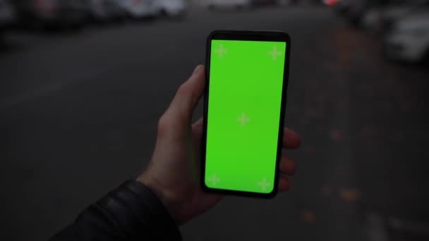 Pov αρσενικό χέρι κρατώντας πράσινη οθόνη mockup του smartphone στέκεται στο δρόμο της πόλης νύχτα — Αρχείο Βίντεο