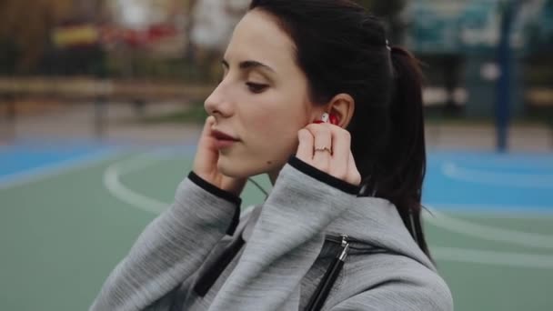 Deporte mujer lleva auriculares inalámbricos en el inicio de su entrenamiento — Vídeo de stock