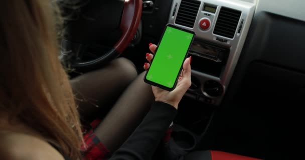 Sexy hembra en falda sosteniendo smartphone con pantalla verde en un coche — Vídeo de stock