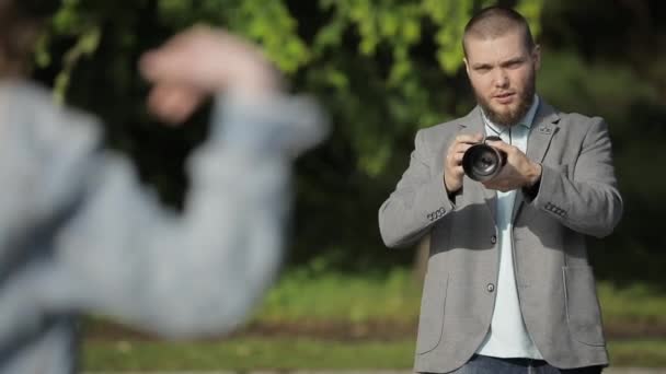 Fotograf gör fotosession medan modell poserar utomhus — Stockvideo