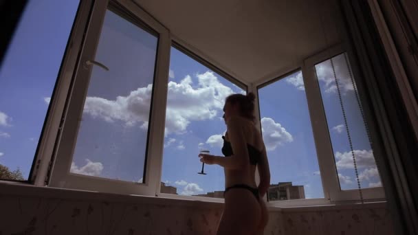 Сексуальная женщина пьет вино на балконе — стоковое видео