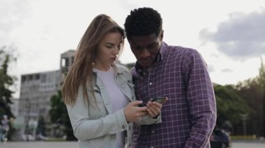 İki çok ırklı arkadaş akıllı telefonlara bakıyor.