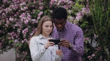 İki çok ırklı arkadaş akıllı telefonlara bakıyor.