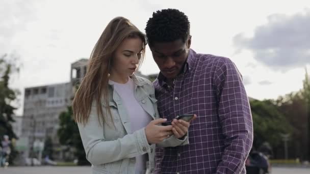 Twee multiraciale vrienden kijken naar beneden in smartphone — Stockvideo