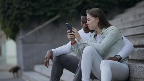 Dos amigos multirraciales mira fotos en el teléfono inteligente — Vídeo de stock