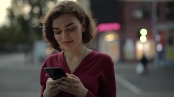 Nő üzenetküldés okostelefonnal séta a város utcájában — Stock videók