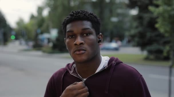 Confiado hombre afroamericano sujetar cremallera de sudadera con capucha en la ciudad — Vídeo de stock