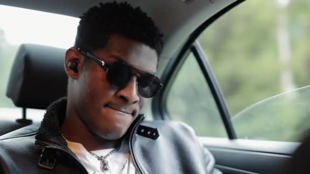 Cool hombre afroamericano escuchar música sentado en un coche — Vídeo de stock