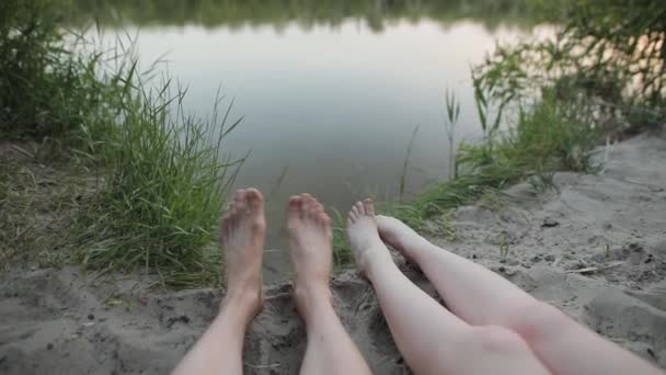 Piernas masculinas y femeninas descalzas cerca del río — Vídeo de stock