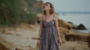 Sahilde yürüyen şık elbiseli bir kadın.