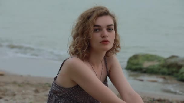 Красива жінка сидить біля морського пляжу — стокове відео