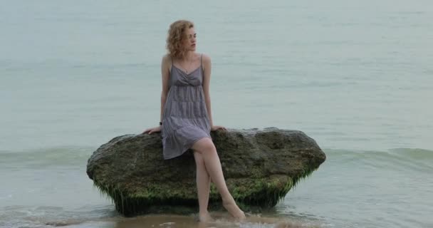 Γυναίκα χαλαρωτική κάθεται σε μια μεγάλη πέτρα στη θάλασσα — Αρχείο Βίντεο